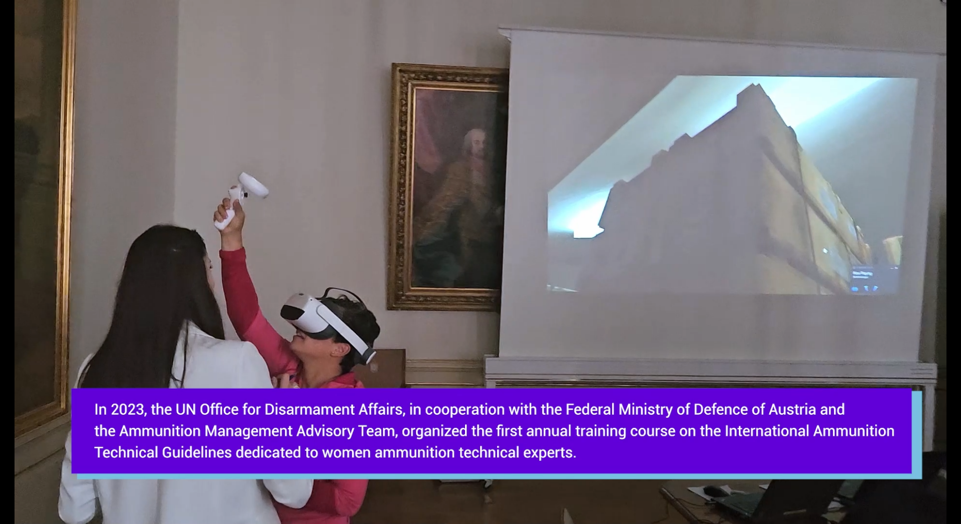 Zwei Frauen vor einer Leinwand, eine trägt eine VR-Brille und hält einen Arm in die Höhe.
