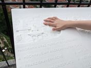 Close-up of the tactile panoramic relief as it is touched by a child's hand.